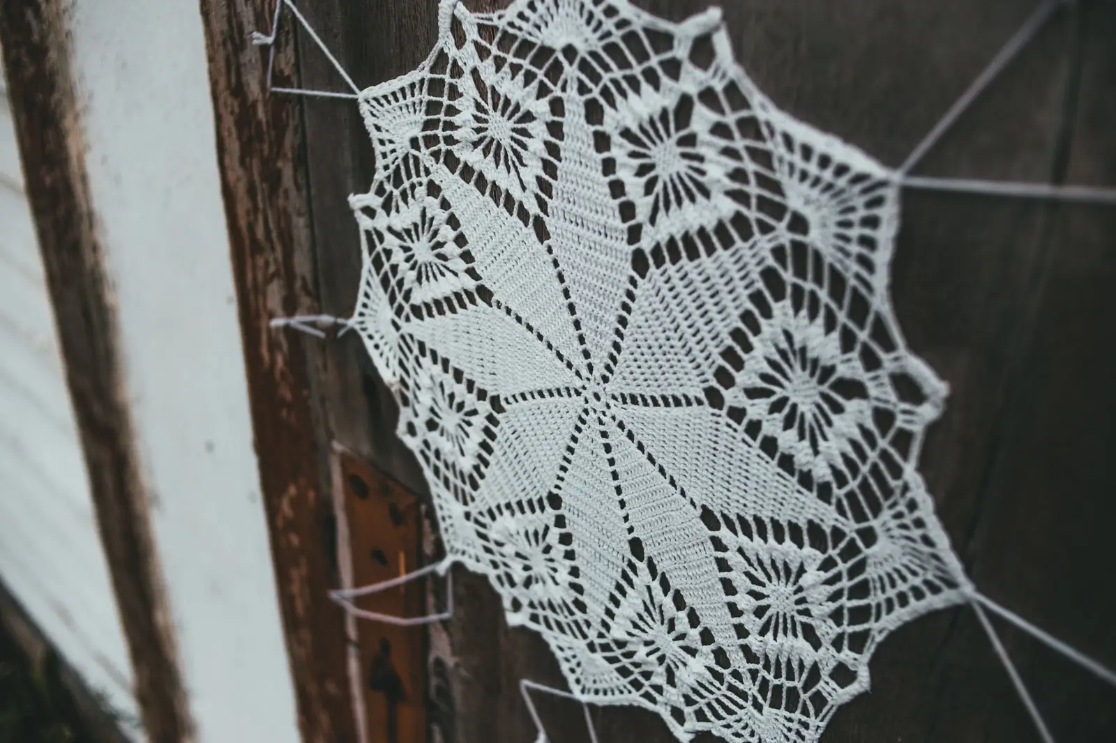 Close-up view of a handmade lace decoration on a rustic wooden door.