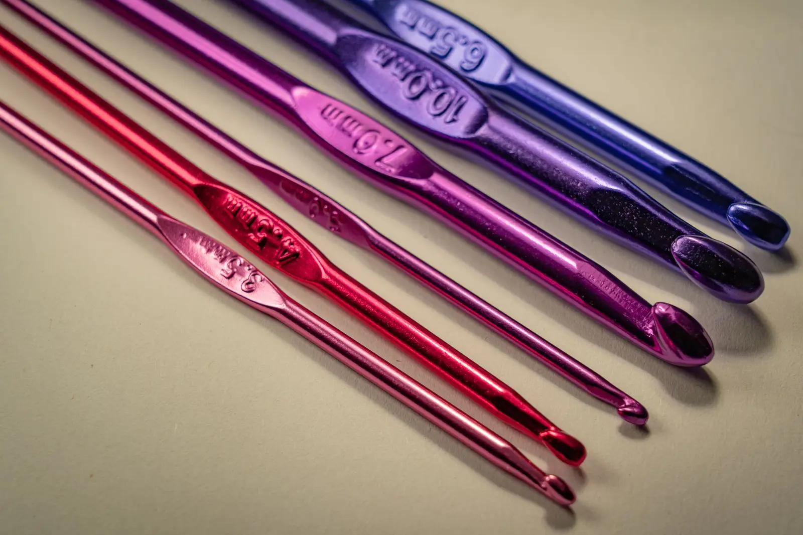 Vibrant set of crochet hooks in multiple colors on a light background.