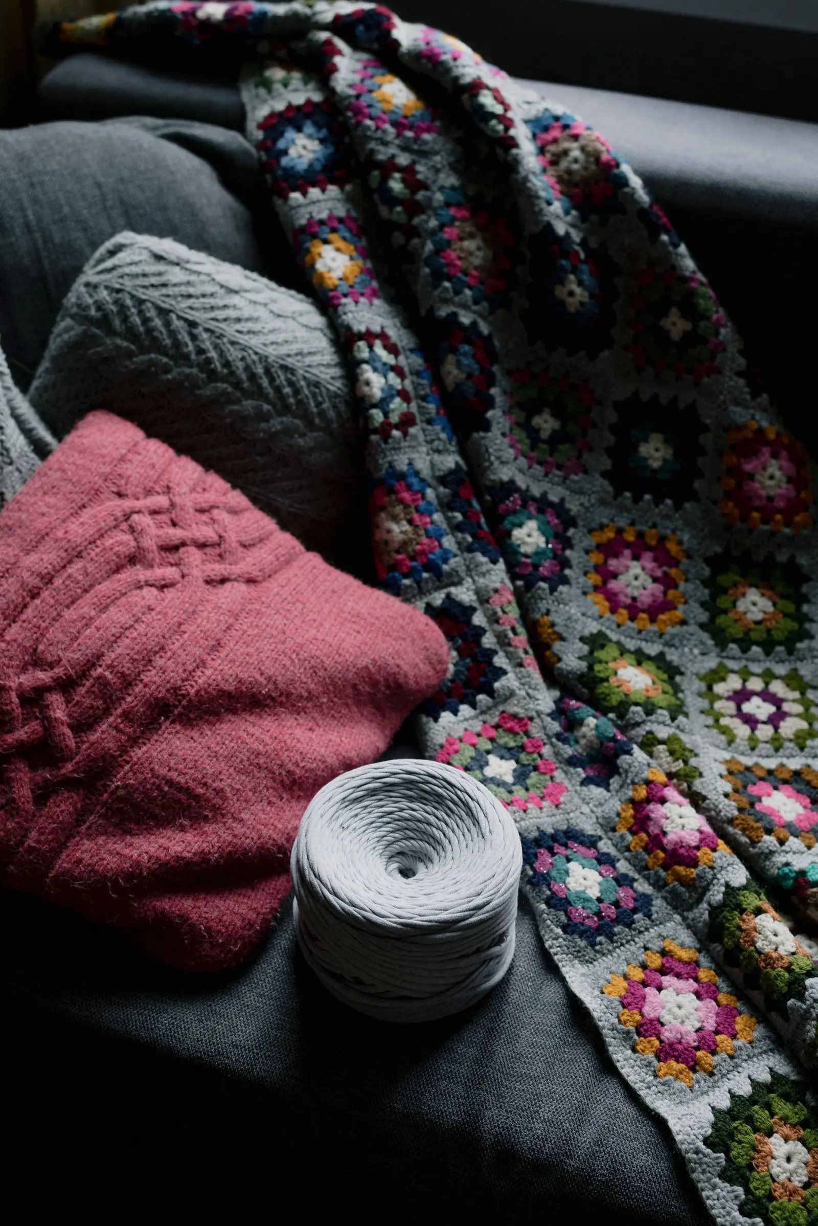 Colorful crochet blanket with yarn on a cozy couch, perfect for winter warmth.